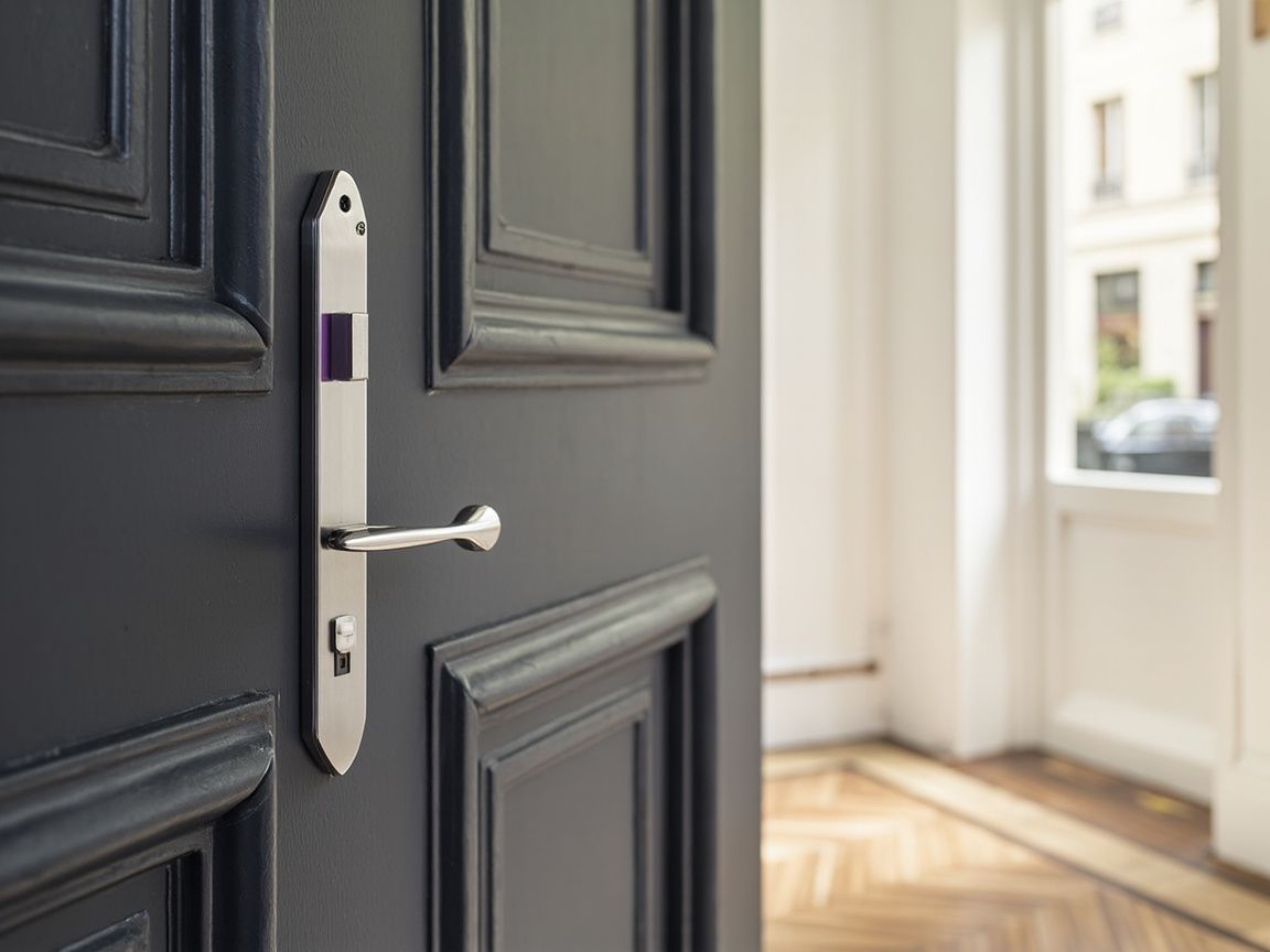 Serrure haute sécurité chromée sur une porte d'appartement parisien
